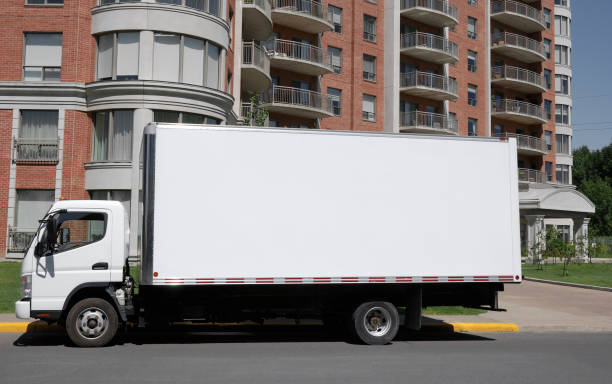 White moving truck park in front of nice condominium building.